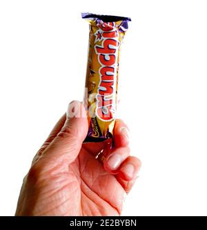 Norwich, Norfolk, Regno Unito – Dicembre 24 2020. Una fotografia editoriale illustrativa di un essere umano non identificabile che detiene una barretta di cioccolato Cadbury Crunchie Foto Stock