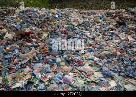 Diverse etichette di bottiglie per animali da compagnia scaricate accanto a un centro di riciclaggio di plastica a Brahmanbaria, Bangladesh. Foto Stock