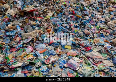 Diverse etichette di bottiglie per animali da compagnia scaricate accanto a un centro di riciclaggio di plastica a Brahmanbaria, Bangladesh. Foto Stock