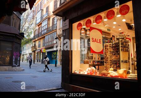 Palma di Maiorca, Spagna. 13 gennaio 2021. Poche persone con maschere passano accanto a negozi chiusi nel centro della città, nel mezzo della pandemia di Corona. Dal 13.01.2021, tutti i ristoranti, i caffè e i bar, così come tutte le palestre e i grandi negozi che non coprono le esigenze di base, tra le altre cose, devono rimanere chiusi sulle isole vacanze spagnole. Inoltre, le riunioni private di persone che non vivono nella stessa famiglia sono vietate a casa e in pubblico. Credit: Clara Margais/dpa/Alamy Live News Foto Stock