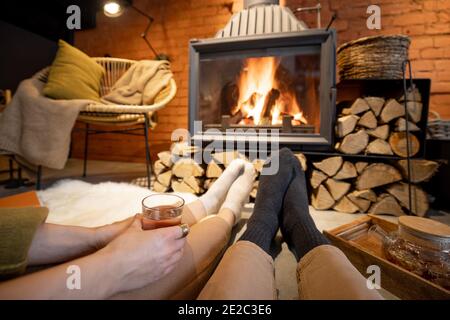 Coppia sdraiata vicino al camino in una casa accogliente in stile loft Foto Stock