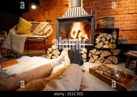 Coppia sdraiata vicino al camino in una casa accogliente in stile loft Foto Stock