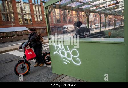 Una persona con consegna in bicicletta con una borsa tote di marca DoorDash accanto a una struttura all'aperto nel quartiere Chelsea di New York mercoledì 6 gennaio 2021. (© Richard B. Levine) Foto Stock