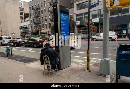 Un uomo usa un chiosco LinkNYC come suo ufficio a Chelsea a New York durante la pandemia COVID-19 di lunedì 11 gennaio 2021. (© Richard B. Levine) Foto Stock