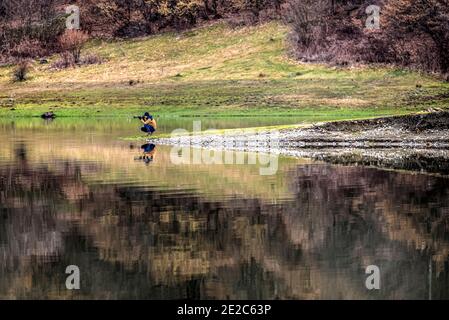 Fotografo della fauna selvatica e la sua riflessione sull'acqua. Foto scattata il 15 marzo 2020 sul Lago di Poiana Marului, contea di Caras-Severin, Romania. Foto Stock