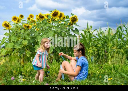 Due bambini sorridenti felici nel campo di girasoli ridono e soffiano bolle. Estate nel villaggio. Foto Stock