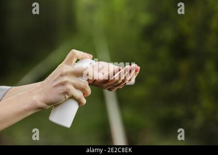 La mano femmina usa una bottiglia cosmetica con schiuma per pulire. Prodotti cosmetici naturali biologici SPA per corpo e viso. Prodotti per la cura della pelle su sfondo verde naturale Foto Stock