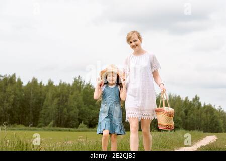 madre e figlia che camminano nella foresta e tenendo hands.walk lungo il percorso. campo e natura. Cesto di vimini. Amore materno, infanzia felice. Foto Stock