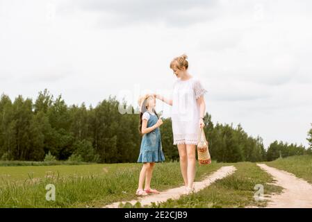 madre e figlia che camminano nella foresta e tenendo hands.walk lungo il percorso. campo e natura. Cesto di vimini. Amore materno, infanzia felice. Foto Stock