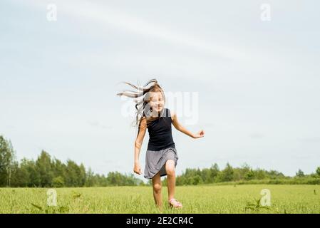 Ragazza, saltando nel field.running e saltando. Felice infanzia, calde estati, libertà e stile di vita. Vento nei capelli Foto Stock