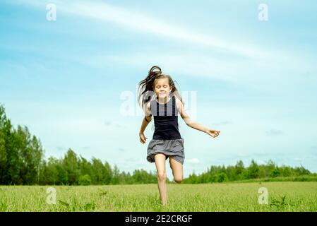 Ragazza, saltando field.running e saltando. Felice infanzia, calde estati, libertà e stile di vita. Vento nei capelli Foto Stock