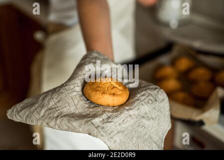 il teengirl in cucina tira fuori i biscotti caldi e il pan di zenzero dal forno. torte fatte in casa, dolci e torte. cottura fatta in casa, vita domestica Foto Stock