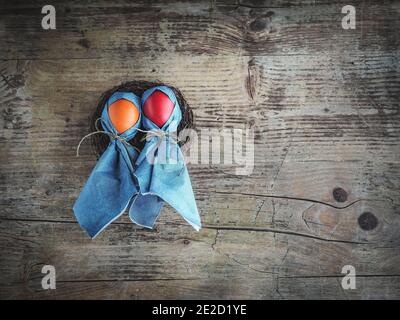 Bambole realizzate con uova colorate e tovaglioli blu. Decorazione pasquale su tavolo di legno. Foto a soffitto con spazio per la copia. Foto Stock