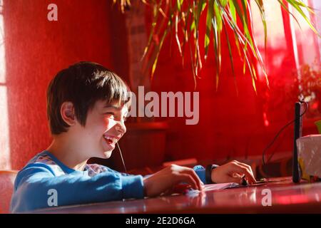 Home formazione online, un ragazzo che utilizza un telefono cellulare e cuffie è impegnato in lingua inglese Foto Stock