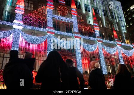 NEW YORK, STATI UNITI - 19 dicembre 2020: I visitatori guardano una mostra luminosa sulla facciata del negozio Saks Fifth Ave prima di Natale a New York City Foto Stock