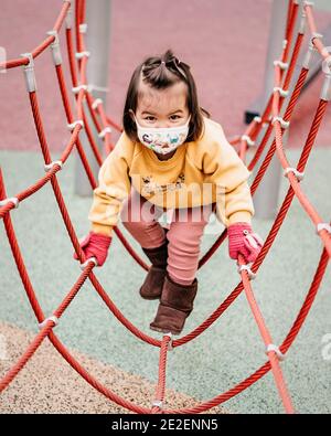 Il bambino gioca nel parco giochi con una maschera Foto Stock