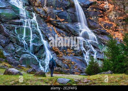 Giovane uomo che ammira le cascate del Nardis in Val di Genova, Parco Naturale Adamello-Brenta nel nord Italia Foto Stock