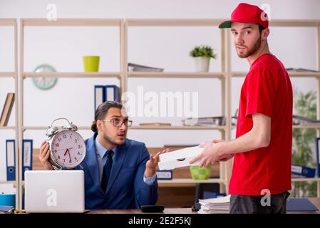 Giovane uomo che consegna la pizza in ufficio in gestione del tempo concetto Foto Stock