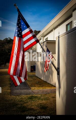 Bandiere americane volano orgogliosamente, prendendo il sole del mattino, in un cortile di fronte. Foto Stock