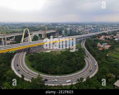 Vista aerea del drone della strada di raccordo autostradale multilivello con auto in movimento e nube di rumore. BEKASI, INDONESIA : GENNAIO 14 2021 Foto Stock