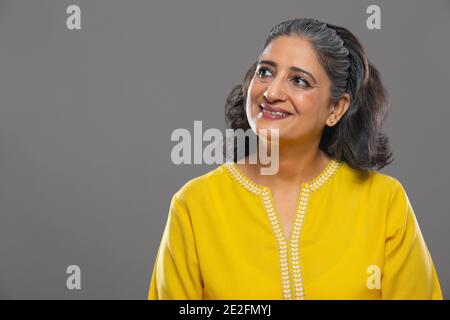 UNA DONNA ADULTA ANZIANA CHE GUARDA VIA E SORRIDE Foto Stock