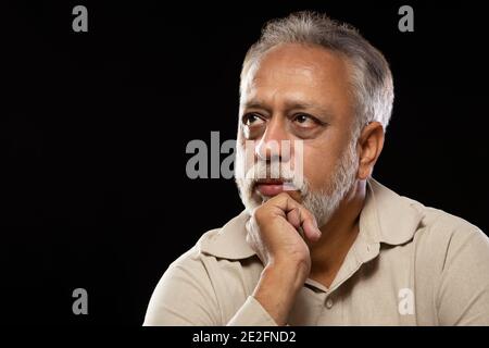 UN UOMO ANZIANO CHE GUARDA SOPRA E PENSA Foto Stock