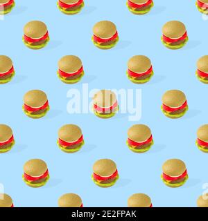 Hamburger giocattolo in plastica per bambini senza cuciture con insalata, pomodoro, carne su sfondo blu. Hamburger giocattolo. Hamburger di plastica. Modello di cibo Foto Stock