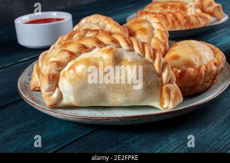 Empanada primo piano con salsa rossa su un blu scuro sfondo di legno Foto Stock