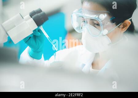 Medico o scienziato che utilizza una pipetta per far cadere un campione a. provetta in laboratorio di ricerca medica o in laboratorio scientifico Foto Stock