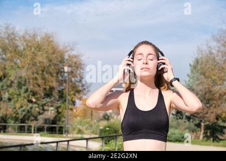 Donna caucasica rossa che indossa le cuffie. Fitness e sport all'aperto. Foto Stock