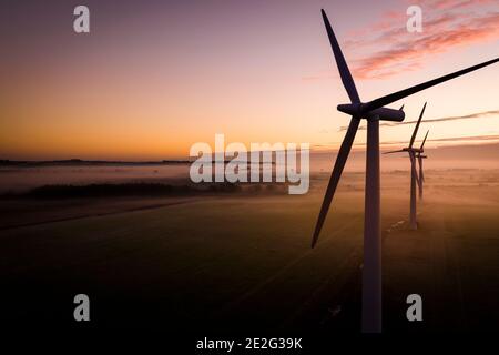 Vista aerea di tre turbine eoliche al mattino presto Nebbia all'alba nella campagna inglese Foto Stock