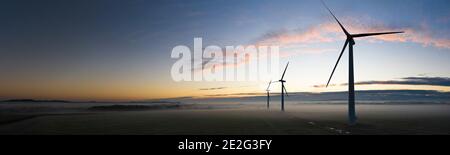 Vista aerea di tre turbine eoliche al mattino presto Nebbia all'alba nella campagna inglese panoramica Foto Stock