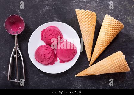 piatto di cialde di gelato al mirtillo e coni di cialde su sfondo scuro, vista dall'alto Foto Stock
