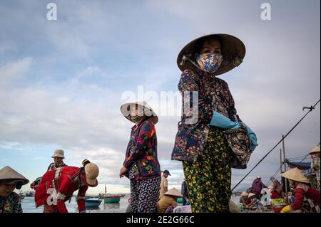 Uomini e donne che lavorano in un mercato del pesce sulla spiaggia, Mui NE, Vietnam Foto Stock