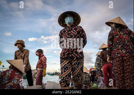 Uomini e donne che lavorano in un mercato del pesce sulla spiaggia, Mui NE, Vietnam Foto Stock