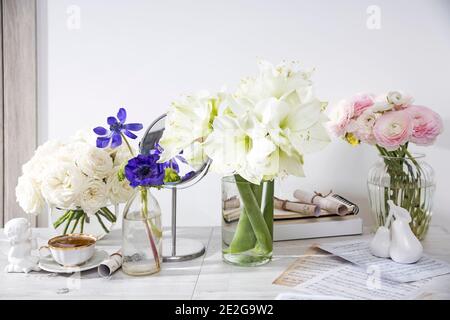 Rose bianche, ranuncolo, anemoni azzurri, coppe giallastre, gigli in vasi rotondi sulle scatole di legno sul tavolo per un'occasione speciale come un fossato Foto Stock