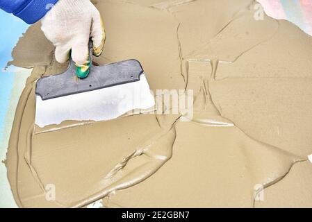 operaio in guanti mette gesso con spatola. riparazione, costruzione Foto Stock