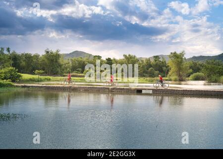 Provincia di Phu Yen, Viet Nam - 9 luglio 2017: In un tranquillo villaggio nella provincia di Phu Yen, Vietnam, bambini che giocano e pedalano sulla piccola strada nel malato Foto Stock