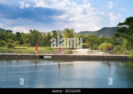 Provincia di Phu Yen, Viet Nam - 9 luglio 2017: In un tranquillo villaggio nella provincia di Phu Yen, Vietnam, bambini che giocano e pedalano sulla piccola strada nel malato Foto Stock