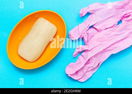 Saponetta e guanti di protezione rosa su sfondo blu Foto Stock