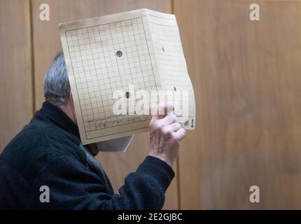 Hannover, Germania. 14 gennaio 2021. Il convenuto entra nel tribunale regionale con una copertina davanti al viso. All'inizio di un processo per omicidio, un uomo di 64 anni negò di aver adorato la sua fidanzata con spiriti metilati e di farla fuoco. Ancora non sa perché ha bruciato, il convenuto ha avuto il suo avvocato di difesa spiegare nel tribunale regionale. Credit: Julian Stratenschulte/dpa/Alamy Live News Foto Stock