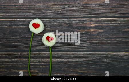 Due rose bianche con cuori rossi su sfondo di legno. Concetto di giorno di San Valentino o giorno di matrimonio Foto Stock