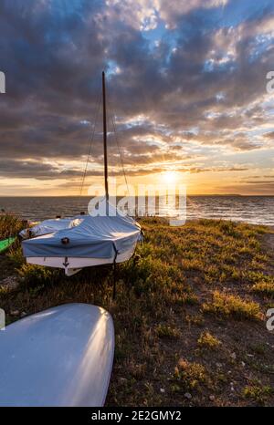 Barche sulla spiaggia di Whitstable sulla costa del Nord Kent al tramonto. Foto Stock