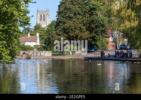 Vista estiva attraverso il laghetto mulino a Tickhill, South Yorkshire con la torre della Chiesa di Santa Maria visibile tra gli alberi che circondano lo stagno Foto Stock