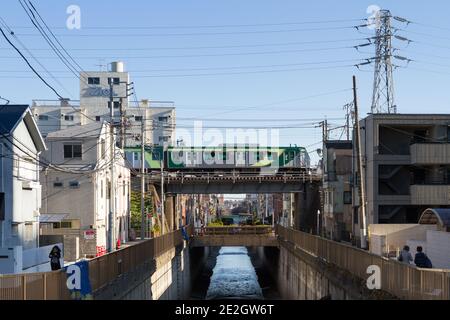 Un treno Tokyu Tamagawa Line serie 7000 su un ponte sopra il fiume Nomi vicino alla stazione di Ishikawa-dai Ota City, Tokyo, Giappone. Foto Stock