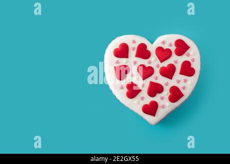 Torta cuore per San Valentino, Festa della mamma o compleanno, decorata con cuori di zucchero su sfondo blu Foto Stock