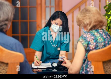 Medico che esamina l'ossigeno nel sangue delle persone anziane utilizzando pulsossimetro durante visita a casa Foto Stock