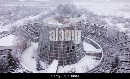 Vecchia serra abbandonata dei tempi sovietici con un design futuristico molto moderno lasciato e dimenticato coperto di neve nel vecchio Parco Botanico in Armenia Foto Stock