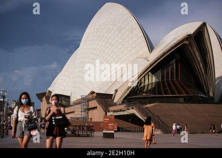 Sydney, Australia. 14 gennaio 2021. La gente passa davanti alla Sydney Opera House a Sydney, Australia, 14 gennaio 2021. La più grande città australiana di Sydney ha registrato cinque casi di COVID-19 acquisiti localmente martedì, mentre le autorità hanno esortato il pubblico ad essere testato e ad aumentare l'apertura e la trasparenza con i traccianti di contatto. Credit: Bai Xuefei/Xinhua/Alamy Live News Foto Stock