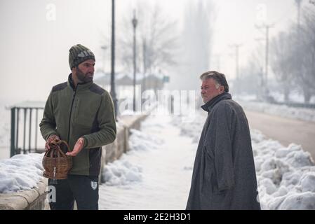 Srinagar, India. 14 gennaio 2021. Gli uomini del Kashmiri parlano sulla riva del lago dal durante una fredda mattina invernale a Srinagar.Notte le temperature del mercoledì sono precipitati ulteriormente attraverso la valle del Kashmir con il mercurio che si stabiliva a meno 8.4°C a Srinagar, la temperatura più bassa di questa stagione finora e la notte di gennaio più fredda negli ultimi 25 anni, I funzionari hanno detto giovedì. Credit: SOPA Images Limited/Alamy Live News Foto Stock